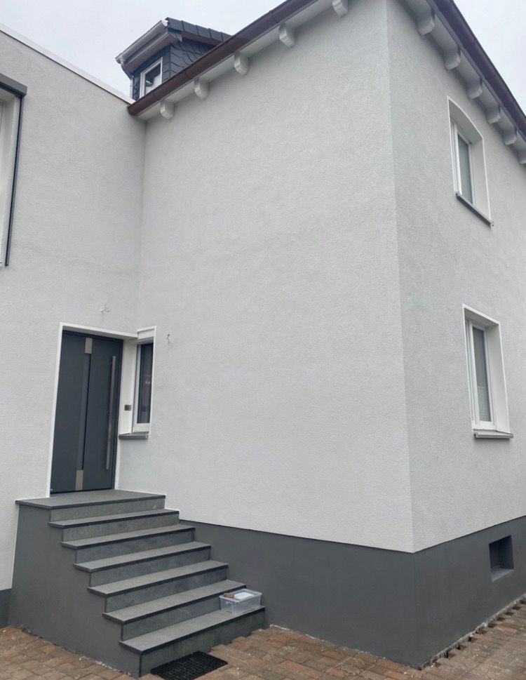 Fertig gestaltete helle Hausfassade mit dunklem Sockel