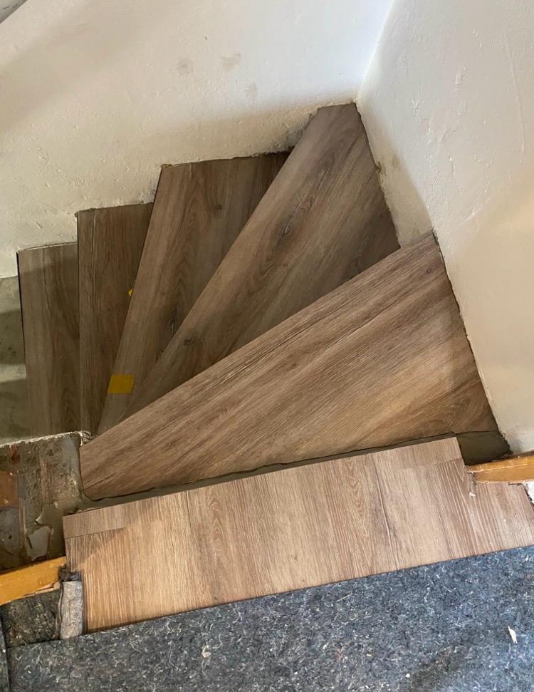 Treppenstufen während der Verlegung eines Bodenbelags in Holzoptik